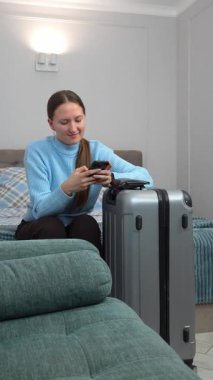 Akıllı telefon planları yapan bir kadın uçak bileti, otel, ulaşım, iş seyahatine hazırlanmak, rotaları kontrol etmek, mobil uygulama dikey video kullanarak taksi çağırmak gibi seyahatler yapar.