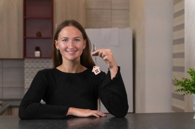 Mutlu ev sahibi yeni mülkünün anahtarlarını gururla tutuyor. Modern ve şık bir mutfakta masada otururken heyecan saçıyor. Hayatında yeni bir sayfa açmaya hazır.