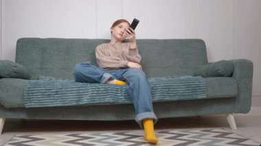 Rahat genç kız boş zamanlarını kanepede oturup televizyon izleyerek geçirmeyi ve loş ışıklı oturma odasındaki kanalı değiştirmek için uzaktan kumandayı kullanmayı seviyor.