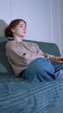 Sıkıntı ve ilgisizlik, genç bir kadını elinde uzaktan kumandayla koltuğunda otururken oturma odasının loş ışığında televizyona bağlanacak bir şey bulmak için çırpınırken tüketir.