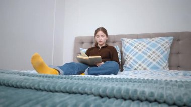 Rahat genç kız kitap okuyor rahat bir yatakta dinlenirken ara sıra durup sessiz bir çalışma sırasında el yazısıyla notlar alıyor.