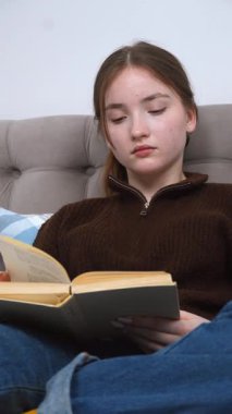 Rahat atmosfer, rahat bir kanepede oturup sayfaları çevirirken ve edebiyat videosuna dalmışken okumaktan zevk alan genç bir kadını çevrelemektedir.