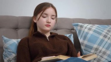 Edebiyata dalmış, rahat bir kanepede kareli yastıkların arasına rahatça oturmuş sakin bir ev keyfi ve sakin bir zamanı kişileştiren özgür genç bir kadın.