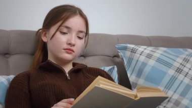 Edebiyata dalmış, rahat bir kanepede kareli yastıkların arasına rahatça oturmuş sakin bir ev keyfi ve sakin bir zamanı kişileştiren özgür genç bir kadın.