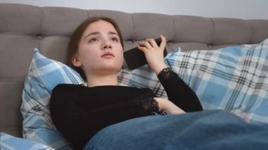 Yatakta rahat rahat uyuyan, sosyal medyada gezinen, mesajlaşan ve rahat ev ortamında dijital içerikle meşgul olan kadın.