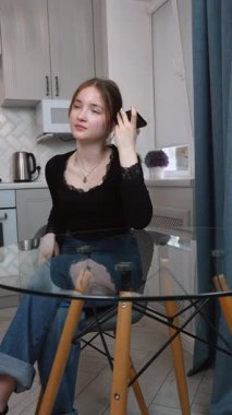 Genç kız akıllı telefonu yüze yakın tutuyor, sesli mesajlar kaydediyor ya da elleriyle konuşmuyor. Akıllı telefondaki sesli asistanı olan kadın rahat beyaz mutfak mobil iletişim uygulamasında