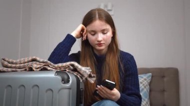 Genç kız otelde yatakta dinleniyor, çantanın yanındaki akıllı telefonu kontrol ediyor, dijital kolaylıkla yaklaşan yolculuğa hazırlanıyor, bir taksi çağırıyor.