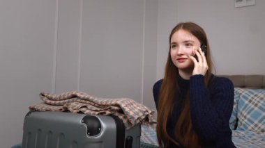 Genç kız otelde yatakta dinleniyor, çantanın yanındaki akıllı telefonu kontrol ediyor, dijital kolaylıkla yaklaşan yolculuğa hazırlanıyor, bir taksi çağırıyor.