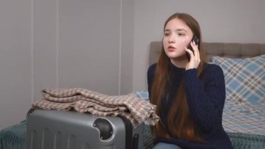 Heyecanlı genç kız valizinin yanında oturuyor, telefon görüşmeleri duygusal bir yolculuğa hazırlanıyor, yaklaşan yolculuktan korkuyor.