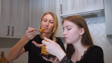 Mutlu aile fertleri tatlı bir anın tadını çıkarıyorlar, katmanlı ballı pastayı tadıyorlar, iç açıcı bir mutluluk sahnesi yaratıyorlar.