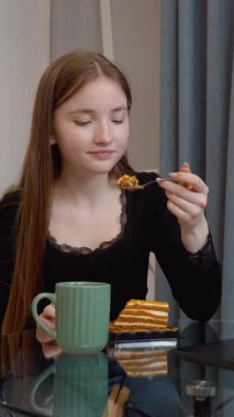 Modern mutfak ortamında, cam masada rahat bir şekilde oturan rahat ofis molası sırasında dizüstü bilgisayar başında çay ve pastanın keyfini çıkaran,