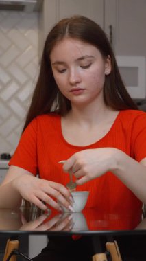 Genç, cam masada oturmuş, günlük evde besleyici atıştırmalıkların tadını çıkarırken,... kaymak gibi yoğurdun tadını çıkarıyor.