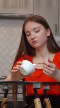 Genç, cam masada oturmuş, günlük evde besleyici atıştırmalıkların tadını çıkarırken,... kaymak gibi yoğurdun tadını çıkarıyor.