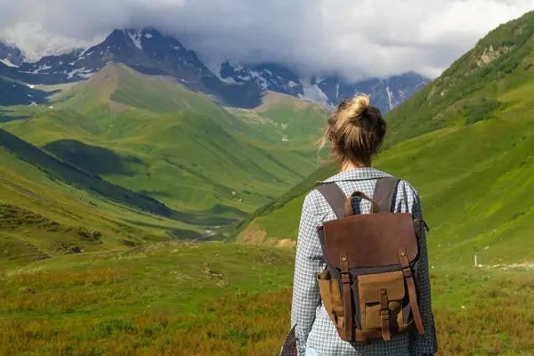 Sırt çantalı genç yürüyüşçü yaz macerası boyunca nefes kesici dağ manzarasının tadını çıkarıyor, doğanın güzelliğini kucaklıyor ve vahşi doğayı keşfediyor..