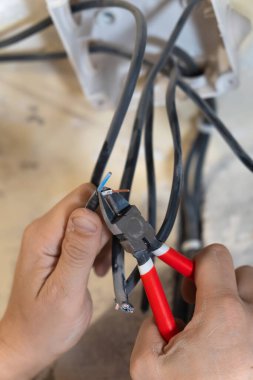 Elektrikçi, elektrik kablolarını titizlikle kesmek ve hazırlamak için kerpeten kullanır. Konut elektrik sistemi üzerinde gerekli bakım işlerini yapar. Dikey fotoğraf