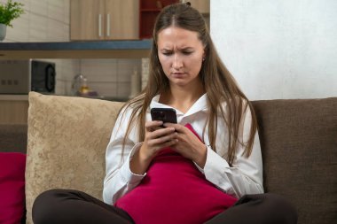 Beyaz gömlek giyen genç bir kadın cep telefonu kullanıyor, internette geziniyor, haberleri okuyor, e-postaları kontrol ediyor, sosyal medyayı karıştırıyor, internette sohbet ediyor, uzaktan çalışıyor, kötü haberler alıyor.