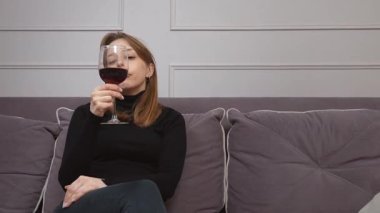 Kolaj, siyah balıkçı yaka kazaklı, elinde altı farklı ifadeyle elinde bir bardak kırmızı şarap tutan ve tadına bakan beyaz bir kadını gösteriyor.