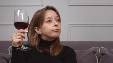 Kolaj, siyah balıkçı yaka kazaklı, elinde altı farklı ifadeyle elinde bir bardak kırmızı şarap tutan ve tadına bakan beyaz bir kadını gösteriyor.