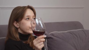 Kolaj, siyah balıkçı yaka kazaklı, elinde altı farklı ifadeyle elinde bir bardak kırmızı şarap tutan ve tadına bakan beyaz bir kadını gösteriyor.