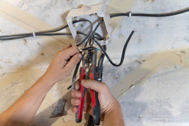 Elektrikçi, elektrik kablolarını titizlikle kesmek ve hazırlamak için kerpeten kullanır.