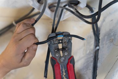 Elektrikçi, elektrik kablosundan yalıtım malzemelerini dikkatlice çıkarmak için kablo sökücüleri kullanır. Elektrik tesisatı ya da onarım projesi sırasında bağlantı için hazırlar.