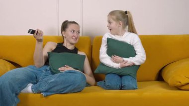 Anne ve kızı sarı bir kanepede oturur, televizyon seyreder, şaşkınlık ve korkudan farklı kanallarda gezinirken heyecan ve kahkahaya kadar birçok duyguyu tecrübe ederler.