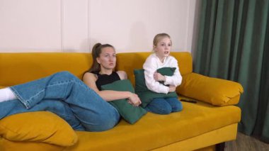 Anne ve kızı sarı bir kanepede oturur, televizyon seyreder, şaşkınlık ve korkudan farklı kanallarda gezinirken heyecan ve kahkahaya kadar birçok duyguyu tecrübe ederler.