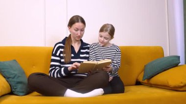 Annem kızına kitap okuyor. Oturma odalarındaki sarı bir kanepede rahat rahat otururken rahat ve eğitici bir ortam yaratıyor.