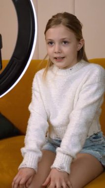 Genç bayan yaratıcı akıllı telefon ve halka ışığı kullanarak video içeriği kaydediyor, sosyal medya materyali dikey video üretirken çok yönlü ifadeler ve dinamik kamera açıları gösteriyor