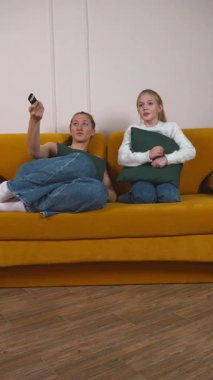 Rahat anne ve küçük kızı canlı sarı koltukta rahat bir şekilde oturur televizyon kanallarını değiştirirken kaliteli zaman geçirir ve birlikte geçirdikleri boş zamanların keyfini çıkarırlar.