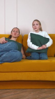 Rahat anne ve küçük kızı canlı sarı koltukta rahat bir şekilde oturur televizyon kanallarını değiştirirken kaliteli zaman geçirir ve birlikte geçirdikleri boş zamanların keyfini çıkarırlar.