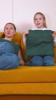 Rahat anne ve küçük kızı canlı sarı koltukta rahat bir şekilde oturur televizyon kanallarını değiştirirken kaliteli zaman geçirir ve birlikte geçirdikleri boş zamanların keyfini çıkarırlar.