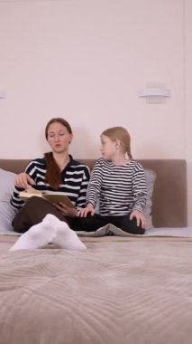 Anne çocuğuna bir kitap okuyor. Kanepede rahatça otururken çeşitli duygu ve ifadeleri gösteriyor. Dikey bir videonun değerli bir anını paylaşıyor.