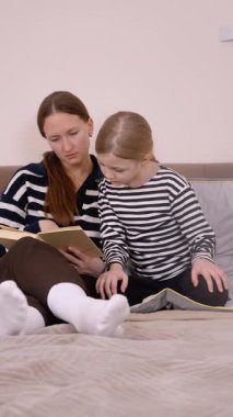 Anne çocuğuna bir kitap okuyor. Kanepede rahatça otururken çeşitli duygu ve ifadeleri gösteriyor. Dikey bir videonun değerli bir anını paylaşıyor.