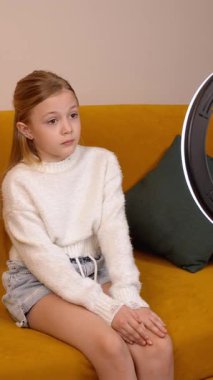 Hevesli genç bir kız rahat bir koltukta oturur, seyircileriyle aktif bir şekilde iletişim kurar ve akıllı telefonuyla bir video blogu kaydeder.