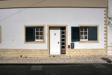 Quiaios, Portekiz - 14 Ağustos 2022: Beyaz boyalı kapı ve pencereli yeşil panjurlu ev