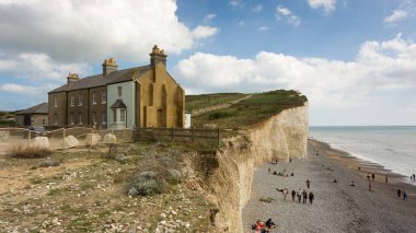 Birling Gap, İngiltere - 10 Eylül 2022: Güneşli bir günde Birling Gap 'ten doğuya bakan Seven Sisters Cliffs' in manzarası kayalıklar, sahil, deniz, insanlar ve uçurumun kenarındaki evleri gösteriyor