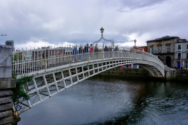 Dublin, İrlanda - 14 Haziran 2024: Liffey nehri boyunca uzanan Ha 'Penny Köprüsü' nün görüntüsü çok sayıda yayanın geçişini bulanık gösteriyor