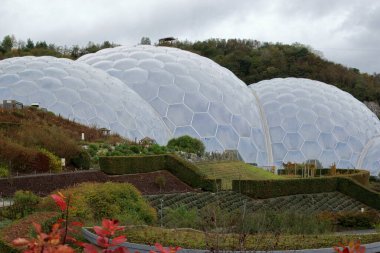 Bodelva, Cornwall, İngiltere - 26 Ekim 2021: Önplanda geniş açık hava bahçeleri ve gri bulutlu gökyüzü ile Eden Projesi biyografilerini kapatın