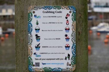 Looe, Cornwall, UK - October 22, 2021: Notice from Marine Conservation Group in harbor detailing crabbing code for how to catch, store and return crabs to sea clipart