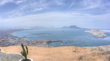 Chimbote, Peru - January 4, 2023: Panoramic view of the city, bay and the Isla Blanca (White Island) taken from Cerro de la Paz (Hill of Peace) with boats and quay visible clipart