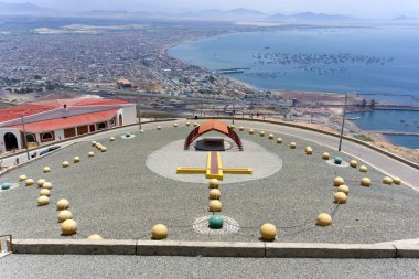 Chimbote, Peru - January 4, 2023: Large scale representation of Rosary beads outside of the church of the Hill of Peace with restaurant and panoramic view of the city and bay in background clipart