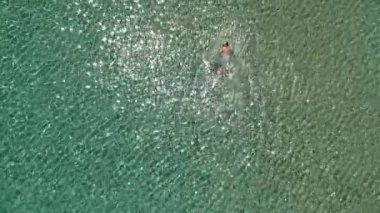 Yunanistan 'ın Alonissos adasındaki kayalık alanda yüzen turistlerin bulunduğu Chrisi Milia plajı üzerindeki hava manzarası.