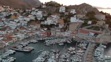 Hava aracı, gün batımında pitoresk liman ve Hydra (veya Ydra) adasının ana köyünün panoramik fotoğrafını çeker. Hydra, Yunanistan 'ın Saronik Körfezi' nde bulunan neoklasik evleri ile önde gelen turizm merkezlerinden biri..
