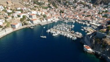Hava aracı, gün batımında pitoresk liman ve Hydra (veya Ydra) adasının ana köyünün panoramik fotoğrafını çeker. Hydra, Yunanistan 'ın Saronik Körfezi' nde bulunan neoklasik evleri ile önde gelen turizm merkezlerinden biri..