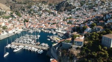 Hava aracı, gün batımında pitoresk liman ve Hydra (veya Ydra) adasının ana köyünün panoramik fotoğrafını çeker. Hydra, Yunanistan 'ın Saronik Körfezi' nde bulunan neoklasik evleri ile önde gelen turizm merkezlerinden biri..