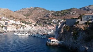 Hava aracı, gün batımında pitoresk liman ve Hydra (veya Ydra) adasının ana köyünün panoramik fotoğrafını çeker. Hydra, Yunanistan 'ın Saronik Körfezi' nde bulunan neoklasik evleri ile önde gelen turizm merkezlerinden biri..