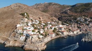 Hava aracı, gün batımında pitoresk liman ve Hydra (veya Ydra) adasının ana köyünün panoramik fotoğrafını çeker. Hydra, Yunanistan 'ın Saronik Körfezi' nde bulunan neoklasik evleri ile önde gelen turizm merkezlerinden biri..