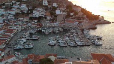 Hava aracı, gün batımında pitoresk liman ve Hydra (veya Ydra) adasının ana köyünün panoramik fotoğrafını çeker. Hydra, Yunanistan 'ın Saronik Körfezi' nde bulunan neoklasik evleri ile önde gelen turizm merkezlerinden biri..