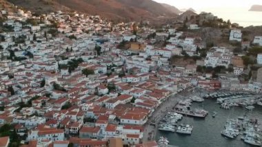 Hava aracı, gün batımında pitoresk liman ve Hydra (veya Ydra) adasının ana köyünün panoramik fotoğrafını çeker. Hydra, Yunanistan 'ın Saronik Körfezi' nde bulunan neoklasik evleri ile önde gelen turizm merkezlerinden biri..